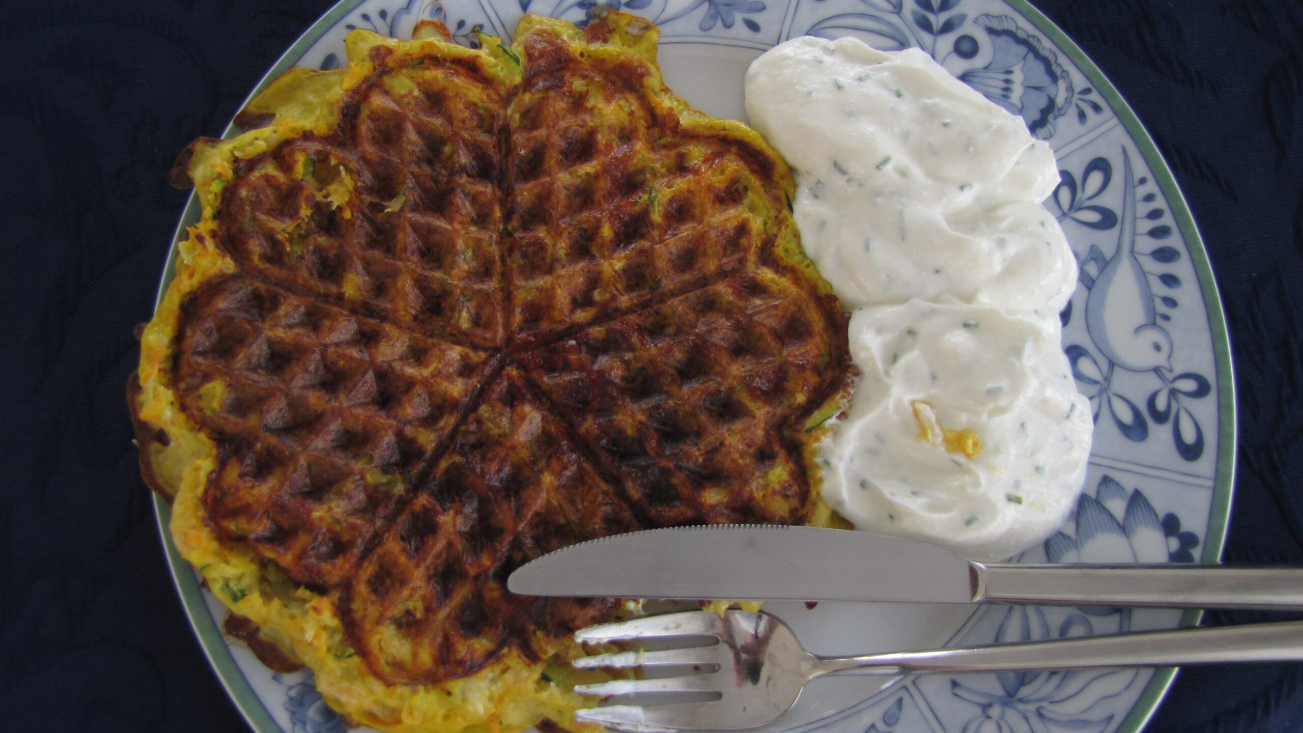 Kartoffel-Gemüse-Waffel mit Quarkdip auf einem blau-weißen Teller