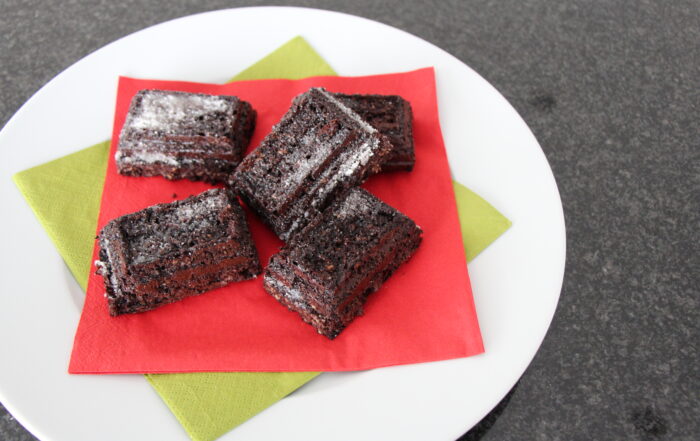 Haferflocken-Brownies mit Joghurt und etwas Puderzucker auf einem Teller