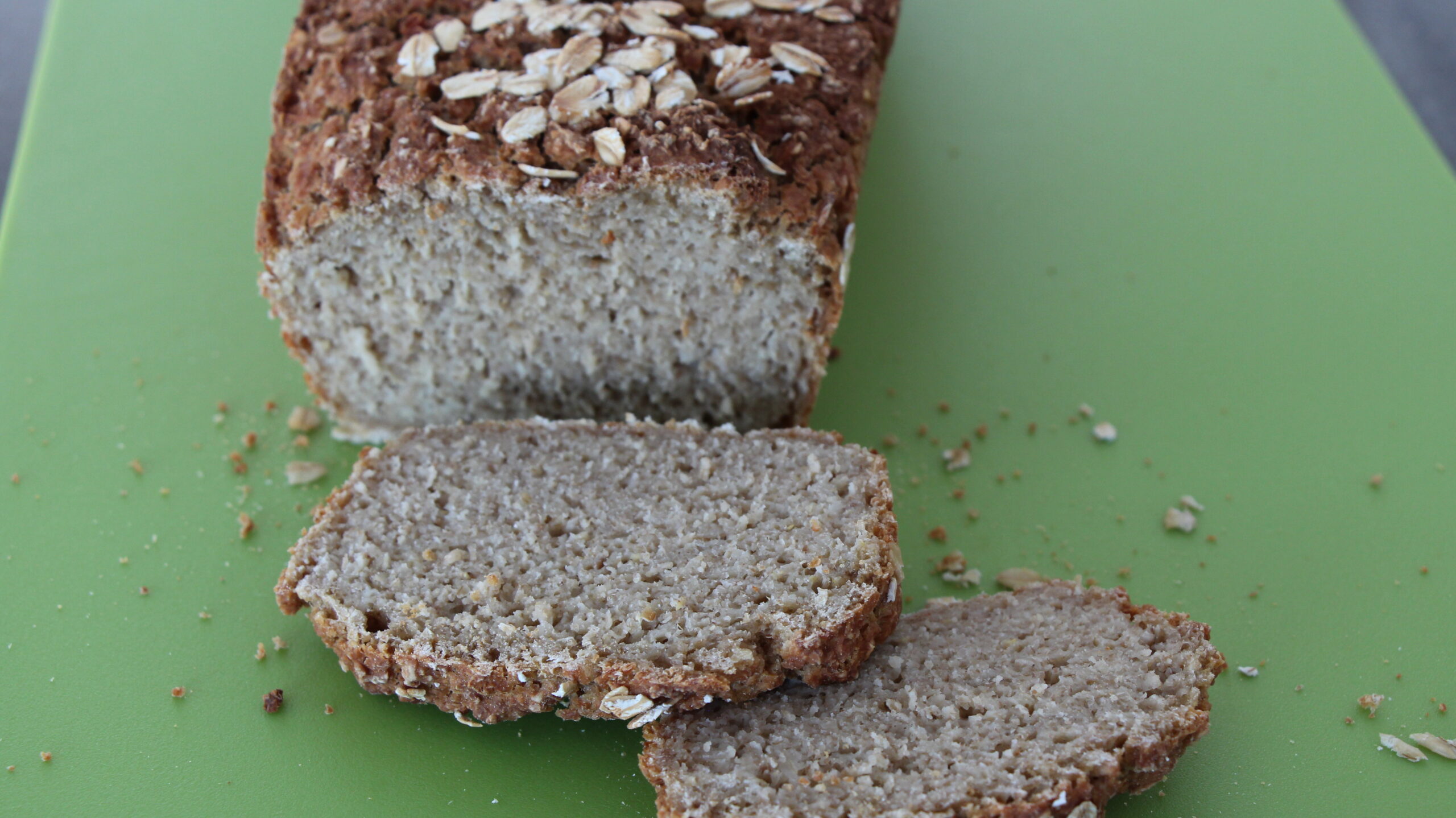 Angeschnittenes Haferbrot mit Haferflocken auf der Kruste und zwei Brotscheiben