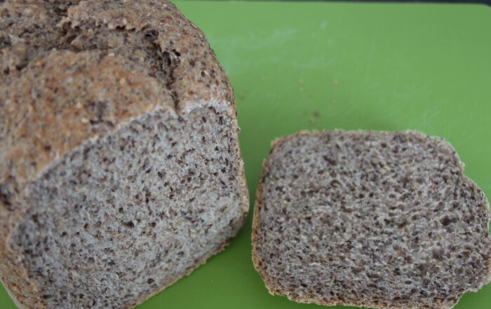 Angeschnittenes Chia-Brot mit Leinsamen und Sesam auf einem grünen Schneidebrett