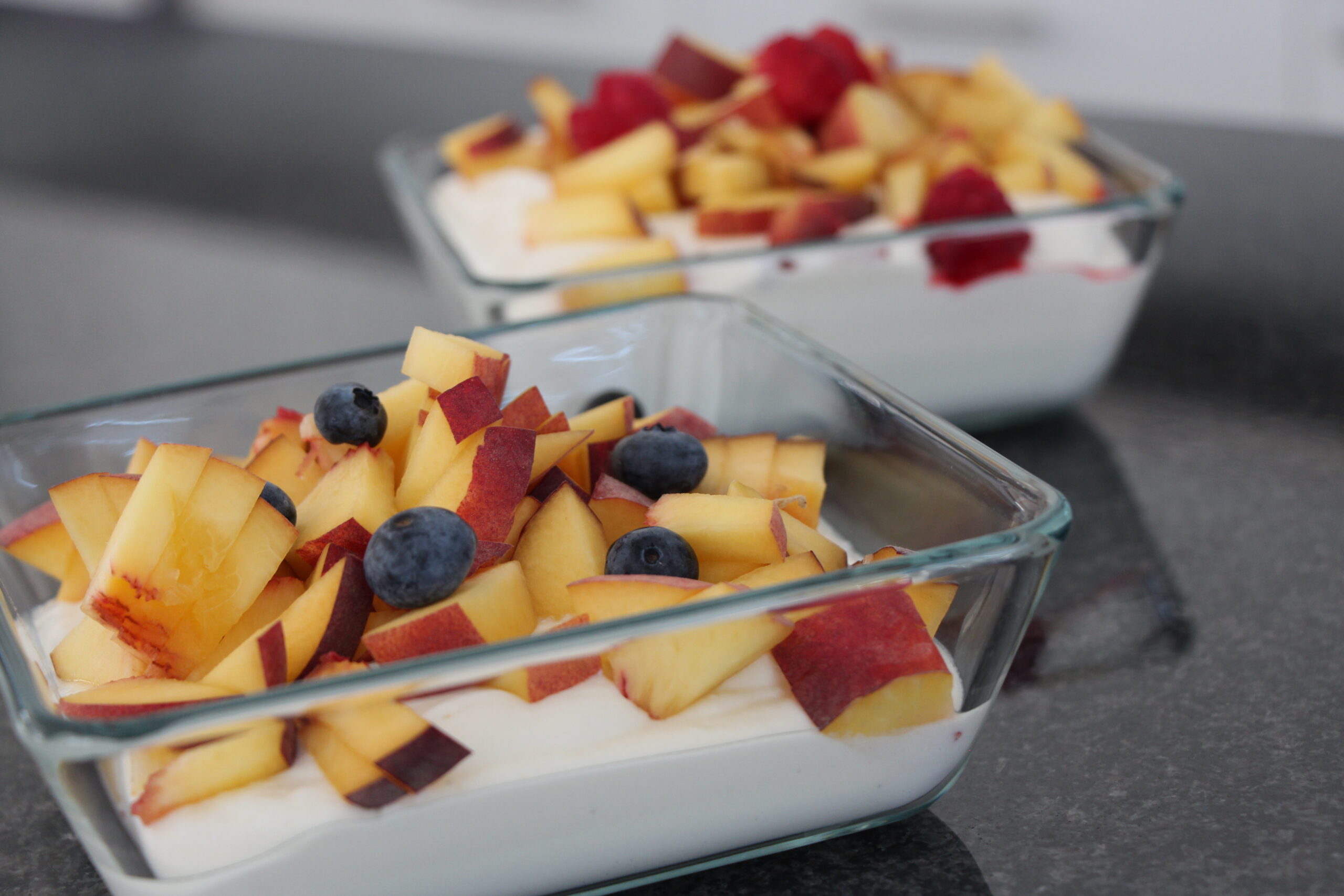 Vanille-Quark-Pudding in Glasschalen mit Pfirsichstücken und Beeren